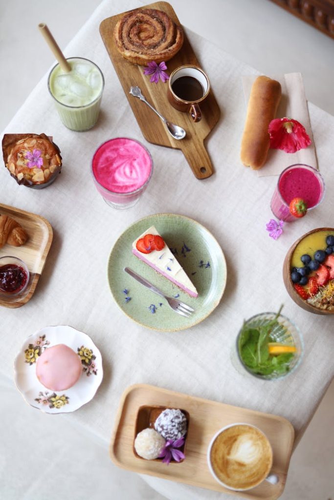 Vibrant flat lay of assorted desserts and beverages on a table setting, perfect for food photography enthusiasts.